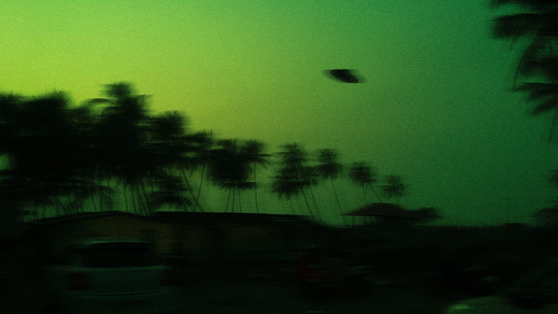 Blurred flying saucer againsrt a green sky