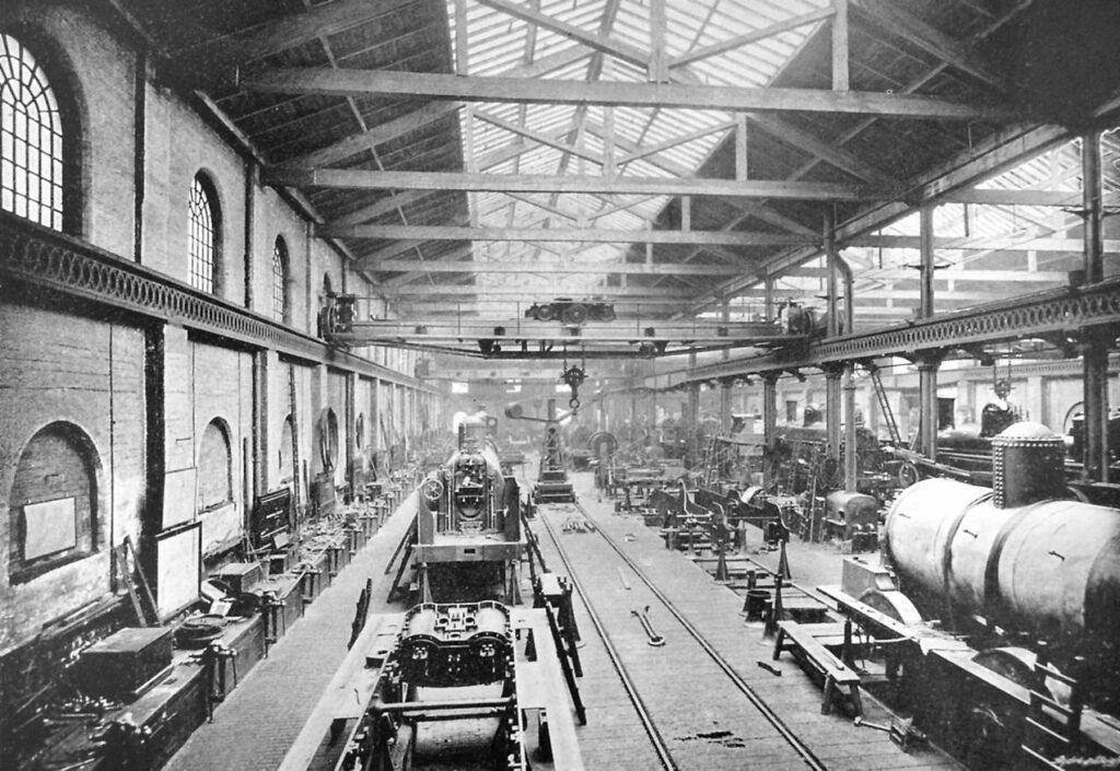 Victorian factory interior showing partially built locomotives on production lines.