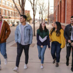 Five students walking along a street chatting and laughing
