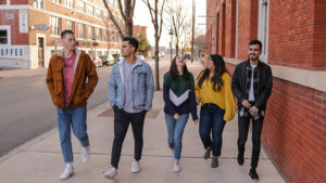 Five students walking along a street chatting and laughing