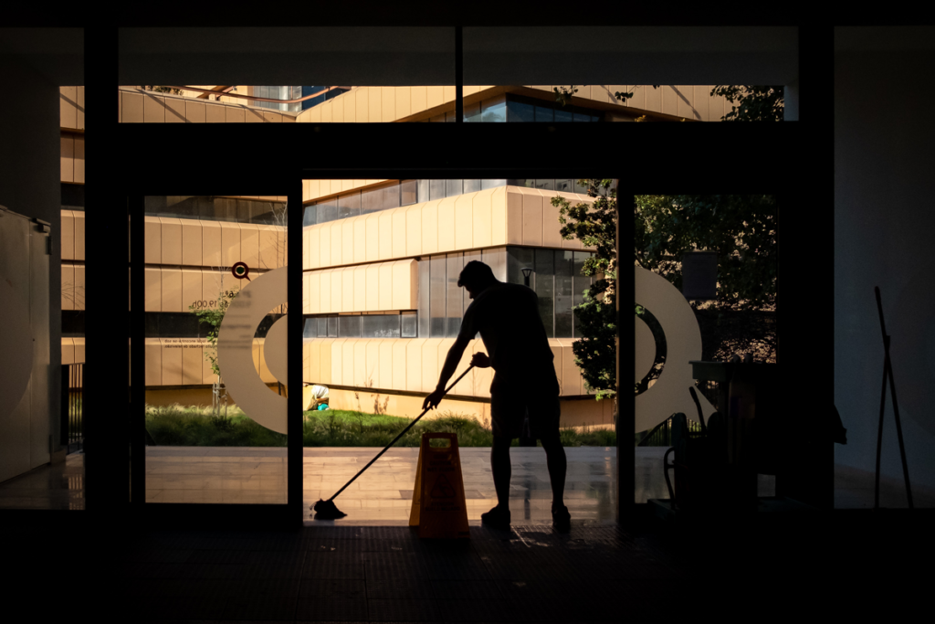 Silhouette of a man mopping the floor of an office building, because the nature of expenses is action or activity.
